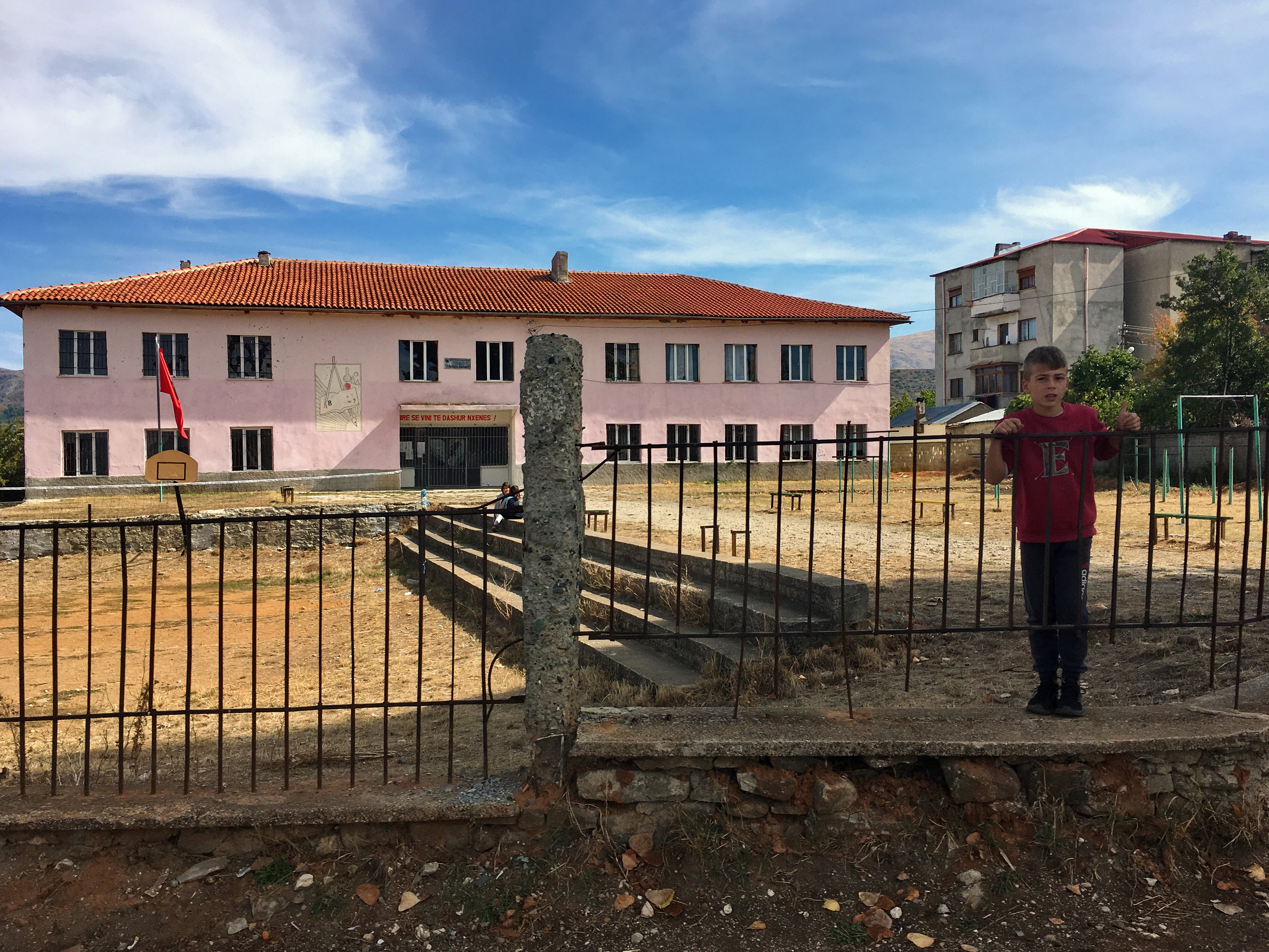 Šola v enem najbolj revnih krajev, ki so jih obiskali. »Kot da bi bil v Etiopiji. Travnato košarkarsko igrišče, koš je bil slab. To sem si res želel fotografirat, ker je bilo grozno.« Ob tem je fotografiral dečka, starega kakšnih deset let. »Shqiptar?« ga je vprašal mali. Luka je odgovoril, da ne. Ko se je obrnil in odšel, je nekaj priletelo na cesto. To ljubko bitje je vrglo nekaj kamnov, a brez zadetka.